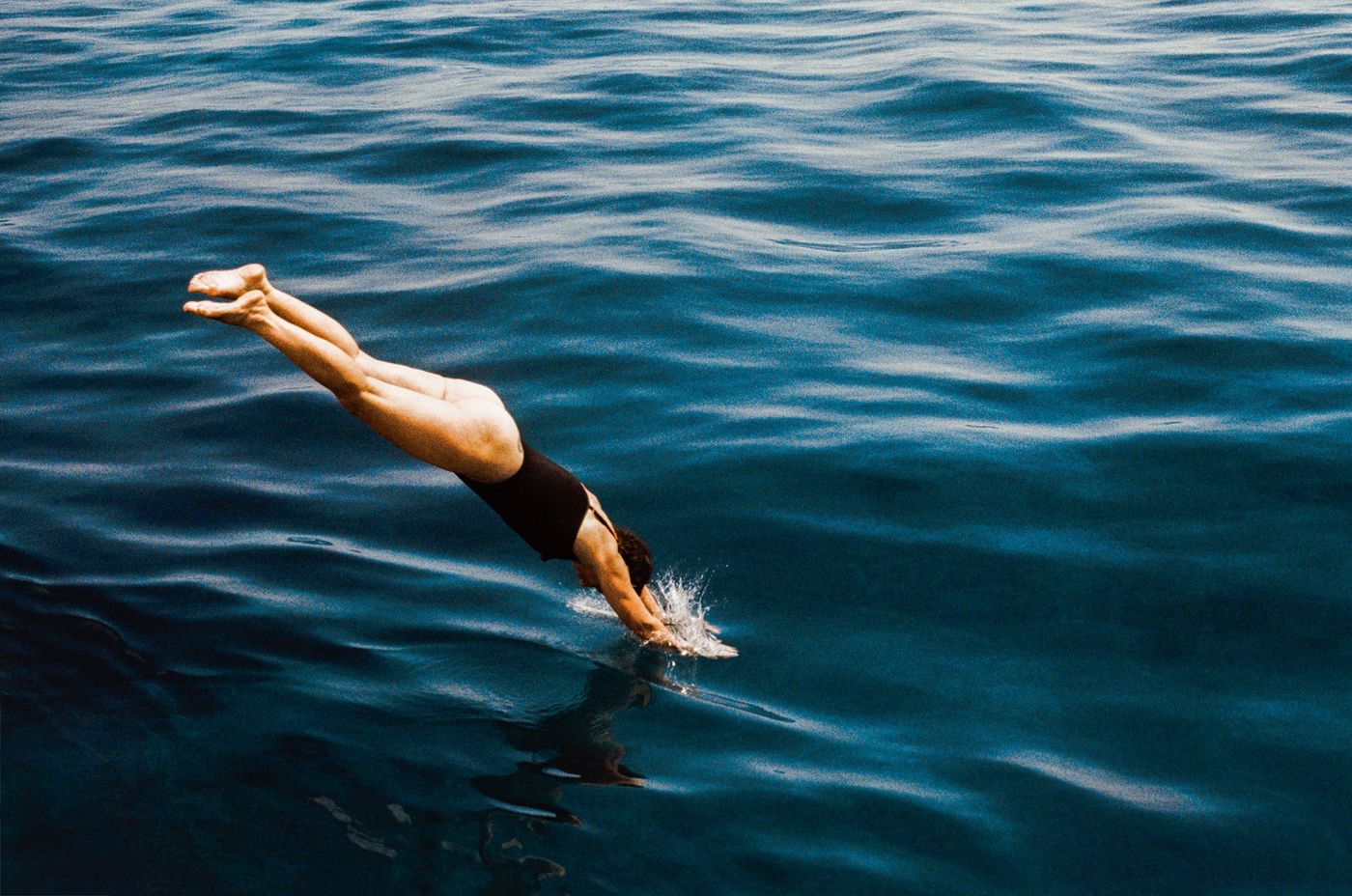 A swimmer diving into deep blue open water