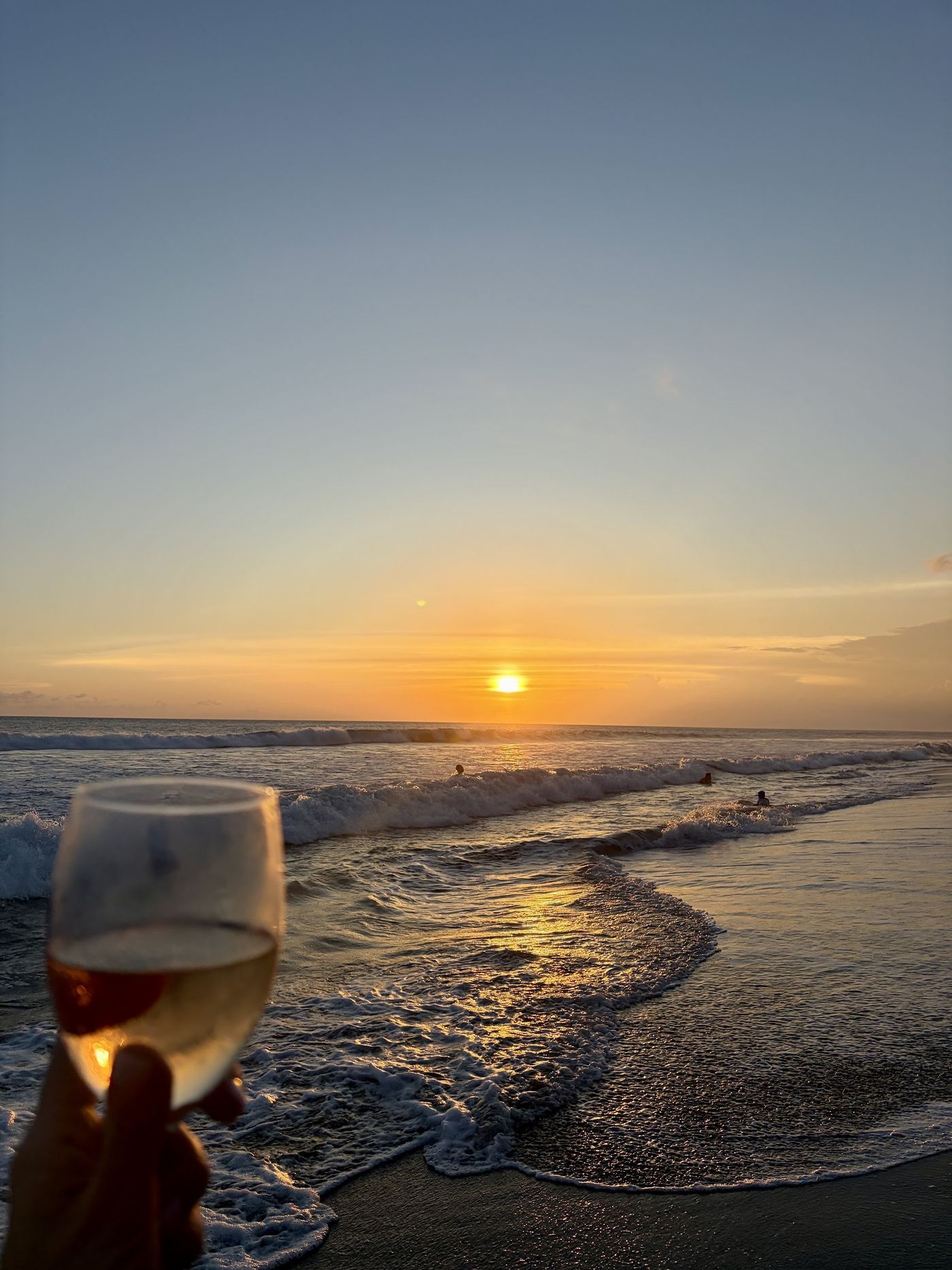 A glass raised against the sea at sunset